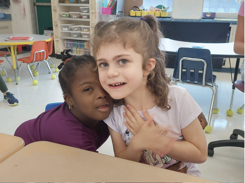 Two students in the REACH program hugging and posing for the camera