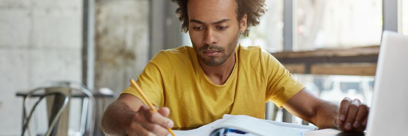 Adult male student studying at a table in a lounge area