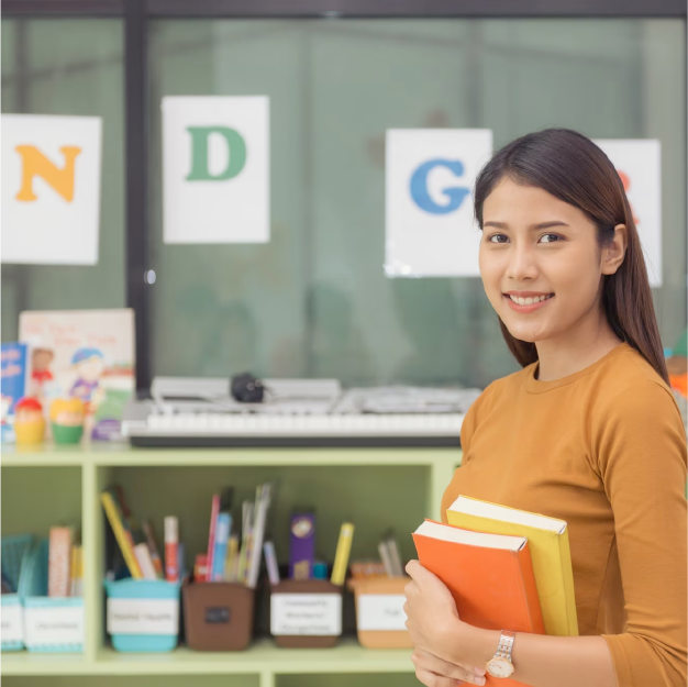 tty asian teacher smiling at camera at back of classroom at the elementary school