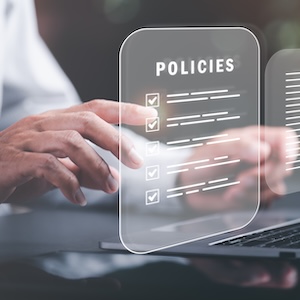 Close up of a man using a computer with the words policy overhead