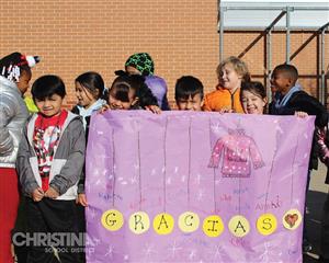 Oberle student with purple banner and yellow circles that read "GRACIAS"