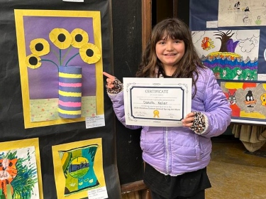 Student showing art work and certificate.