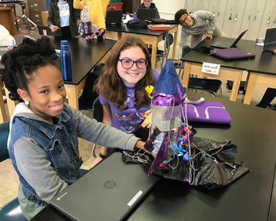 Two female students in the Middle School Honors Program showing off their rocket