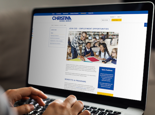 Close up of hands over a laptop keyboard while viewing the Christina School District websit4e